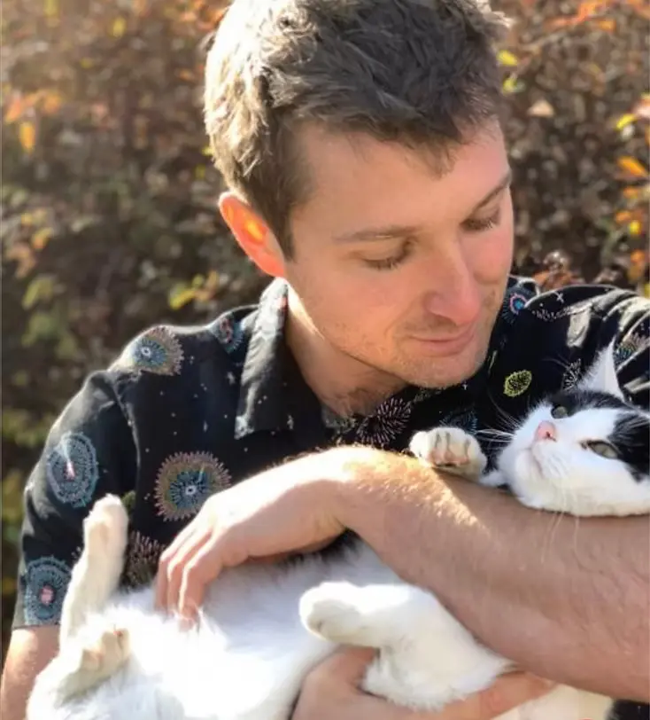 Bruce Kenyon outdoors, holding a black-and-white cat